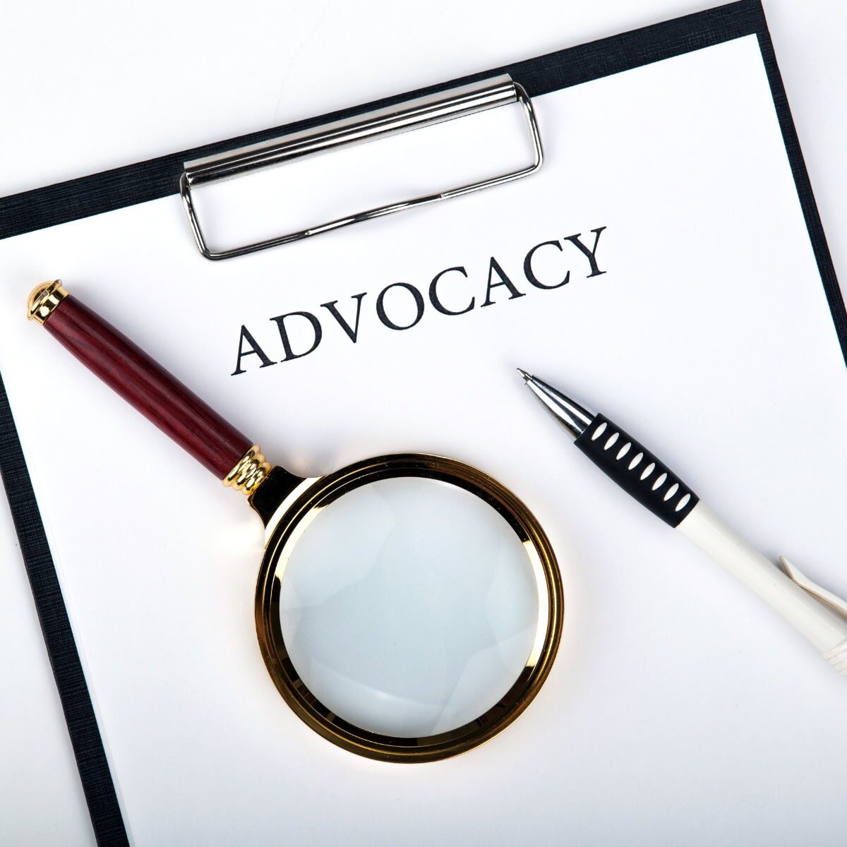 Advocacy-Resources A clipboard featuring a sheet of paper that says advocacy, with pen and a magnifying glass on top