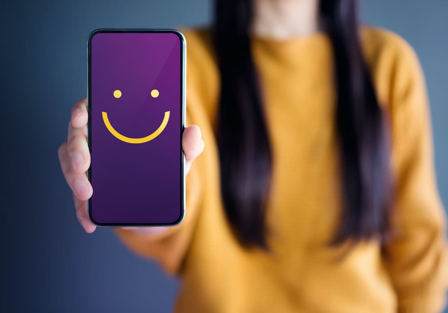 PSAS Woman holding a phone with a yellow smiley face on the screen